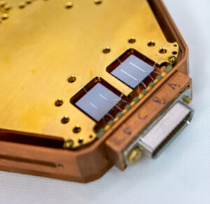 Close-up of a hexagonal structure holding two square chips, each with two reflective lines.